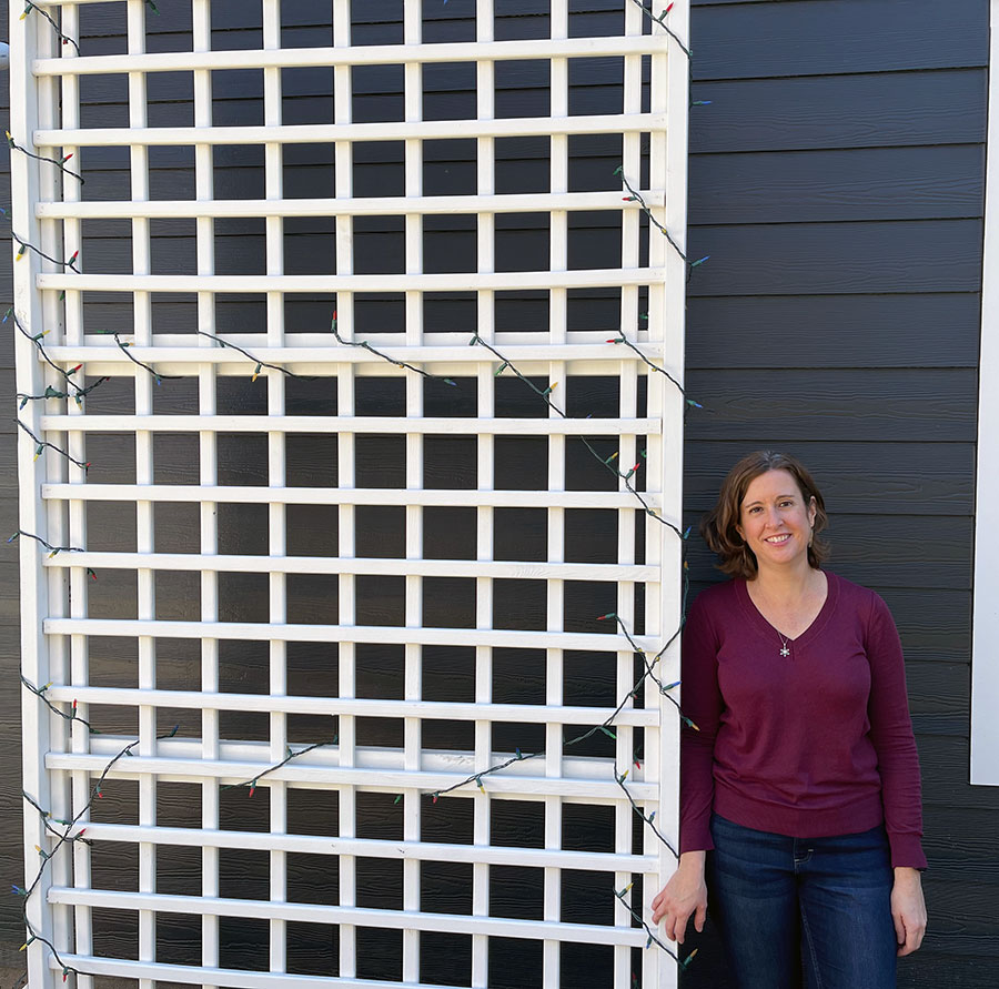 Kathy standing next to the white trellis